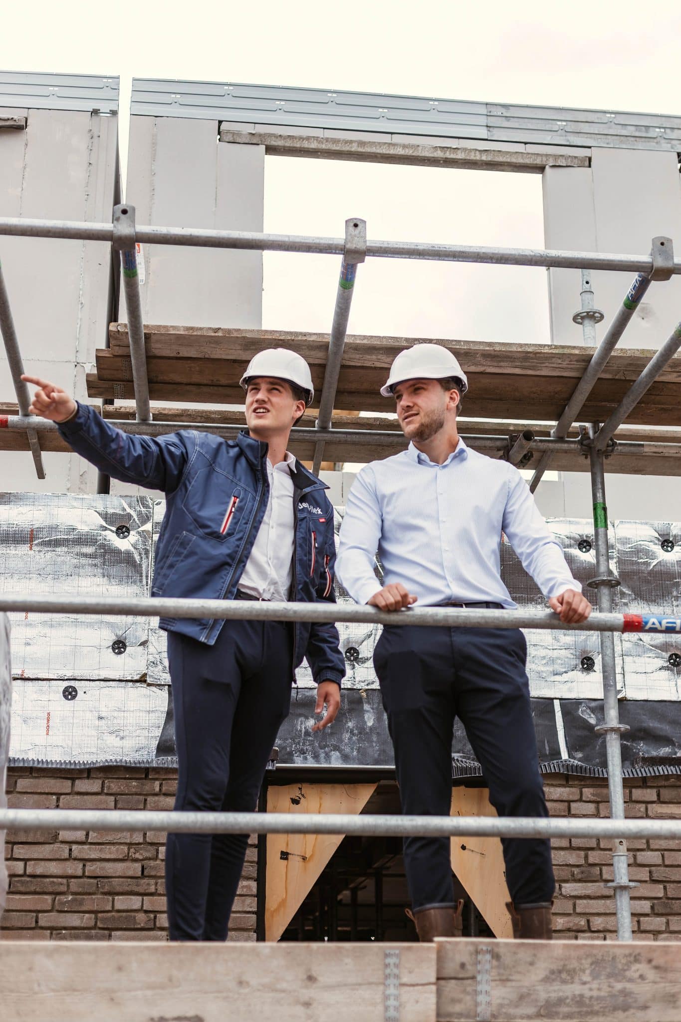 Twee personeelsleden:relatiemanagers van demt-flex op de steiger op de bouwplaats - voor- en nadelen vaste medewerker - demt-flex